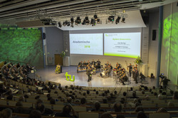 Gesamtansicht Audimax von oben, über die Sitzreihen hin zur Bühne - Der Saal ist in grünes Licht getaucht