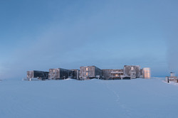 A two-story building with four side wings in the twilight in the snow.