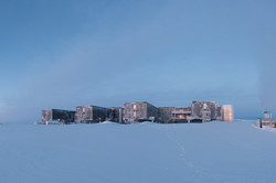 Ein zweistöckiges Gebäude mit vier Seitenflügeln im Dämmerlicht im Schnee.