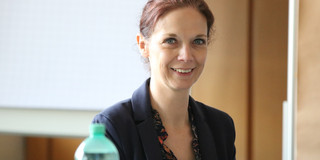 A portrait of a woman wearing a black blouse, the woman is Stephanie Bund.