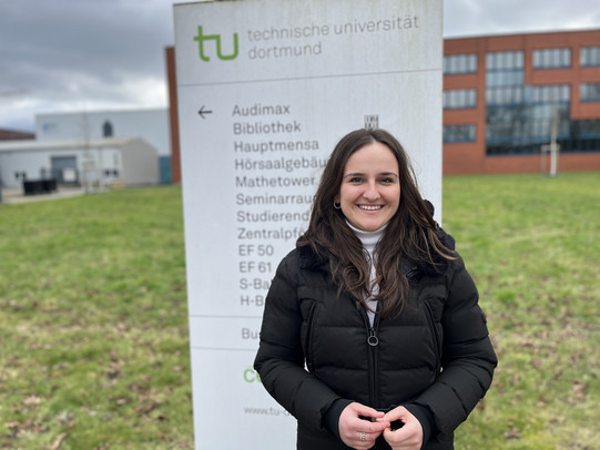 Studentin vor einem TU Dortmund Schild
