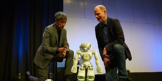 Zwei Männer knien neben einem kleinen Roboter