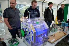 Vier Personen stehen hinter einem 3D-Drucker.