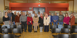 Group picture of several people in a large room with rows of chairs.