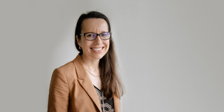 Portrait of a woman against a gray background. The woman is Prof. Natalie Germann.