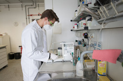Student in lab coat works in the lab