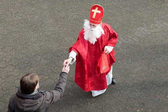 Ein Nikolaus übergibt einem Mann einen Schoko-Nikolaus