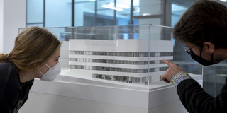Zwei Personen begutachten in einer Ausstellung den Miniatur-Nachbau eines Gebäudes.
