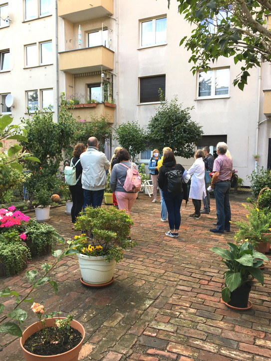 Begrünte Mauer Kirchenstraße Das Bild zeigt eine Gruppe von Menschen in einem begrünten Hinterhof