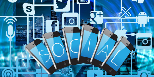Grafik mit Social-Media-Icons und aufgefächterten Mobiltelefonen vor dem Hintergrund einer Skyline