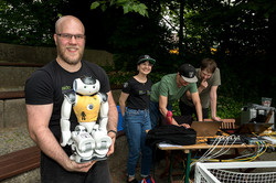 Fußballroboter Eine Person hält einen kleinen Roboter in die Kamera