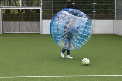 Eine Person in einem Bubble Ball spielt Fußball.