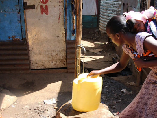 Städtische Wasserlandschaften Afrikas Frau mit Kleinkind füllt Wasser in einen Kanister ab.