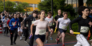 Several people in sports outfits hold a baton and run.