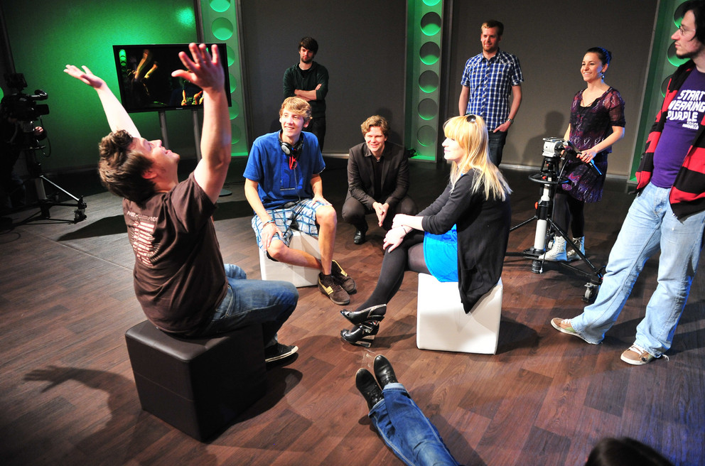 Students are sitting and talking in a TV studio