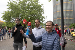 Zwei Männer und eine Frau stehen an einer Startlinie und sind bereit, den Startschuss für einen Lauf zu geben.