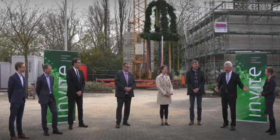 Richtfest Acht Personen stehen auf dem Gelände, auf dem ein Gebäude entsteht.