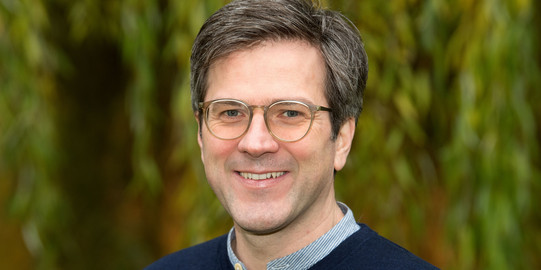 Portraitfoto von Bernd Sommer, im Hintergrund verschwommen eine Trauerweide. 