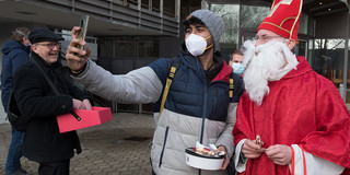 Der Nikolaus macht mit einem Studenten ein Selfie.