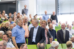 EIn voller Hörsaal mit Menschen im Anzug im Publikum.