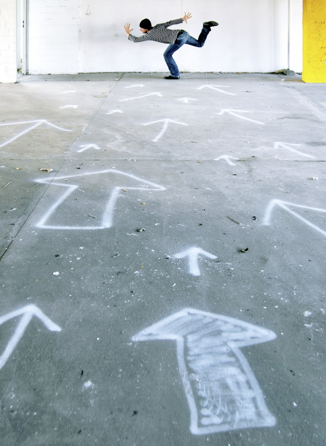 Pfeile aus Kreide auf dem Boden gemalt und eine Person im Hintergrund die "rennt"