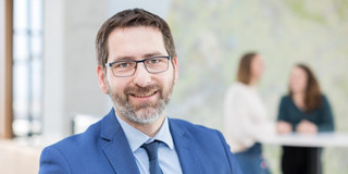 A photo of a man with glasses in a blue suit