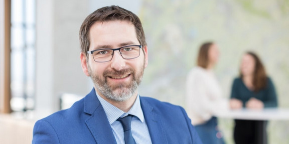 A photo of a man with glasses in a blue suit