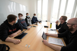 Eine Gruppe von Männern sitzt an einem Tisch und hat iPads in der Hand.