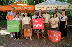 Photo: A group of people stands under pavilions holding cubes with symbols of the Sustainable Development Goals.