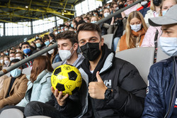 Close-up of a freshman student sitting on a covered bleachers in a soccer stadium holding a soccer.