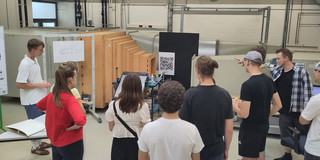 Schüler*innen schauen sich ein Experiment in einer Forschungshalle an