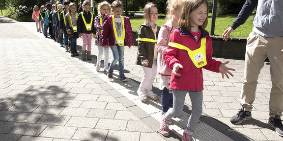 Kinder laufen in einer Schlange über die Rillen des Leitsystems, das Blinden die Orientierung erleichtert.