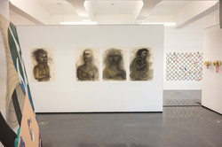 Vier Gemälde, die Abbildungen eines Menschen zeigen, hängen an einer weißen Wand in einem Ausstellungsraum.
