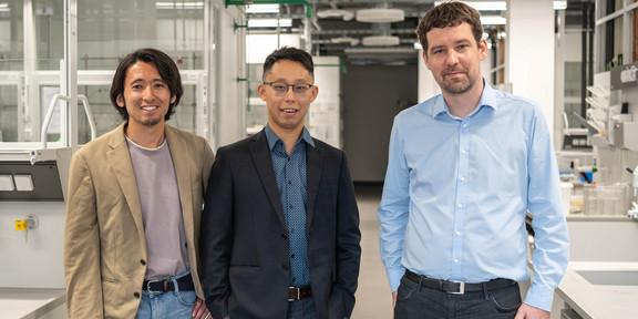 Three men standing in a laboratory.
