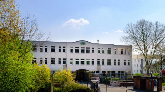 Drei-geschossiges Bürogebäude mit vielen Fenstern und grünem Logo 'CDI' auf der Fassade, umgeben von Bäumen