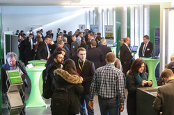 Mehrere Personen stehen in einem Foyer, am Rand sind Informationsstände aufgebaut