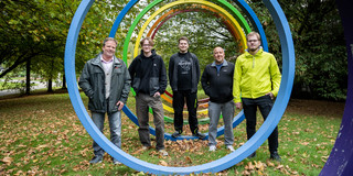 Drei Azubis und ihre Ausbilder stehen auf dem herbstlichen Campus.