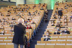 Ein Mann im Anzug steht in einem mit Studierenden gefüllten Hörsaal und hält einen Vortrag.