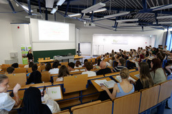 Eröffnungsveranstaltung Teilnehmende sitzem im Hörsaal und füllen eine digitale Umfrage aus.