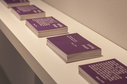 Einige Stapel mit lila Postkarten auf denen Texte stehen