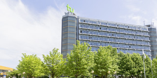 Studierende sind draußen auf dem Campus der TU Dortmund, im Hintergrund steht der Mathe-Tower.