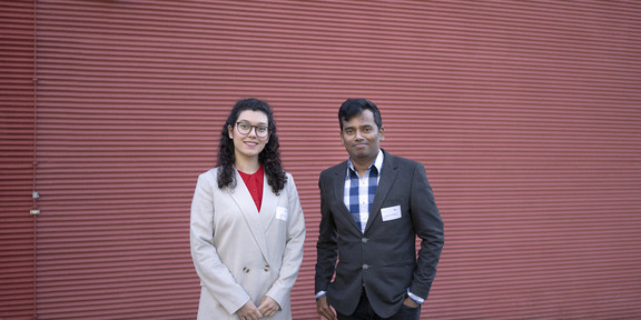 Zahra Bonakdar und Ashutosh Bhagwat Eine Frau und ein Mann stehen draußen vor einer roten Wand