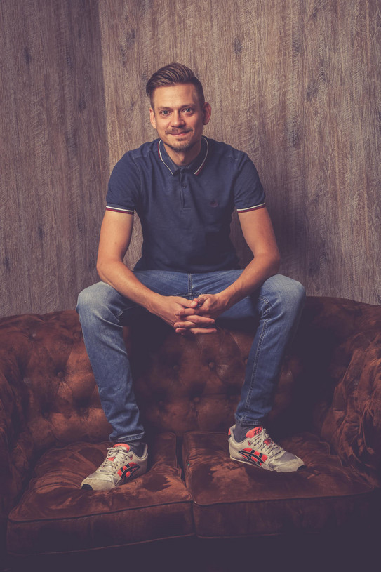 Jan Dahlmann Ein Mann sitzt auf der Lehne eines Sofas.