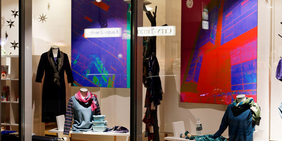 Geguckt in Dortmund _ Kunst im Schaufenster Im Schaufenster eines Modegeschäfts hängen große Fotografien von Häuserfassaden, die mit einem Farbfilter bearbeitet wurden.