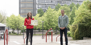 Eine Frau und ein Mann stehen auf dem Martin-Schmeißer-Platz. Die Frau hält einen Silberteller in der Hand.