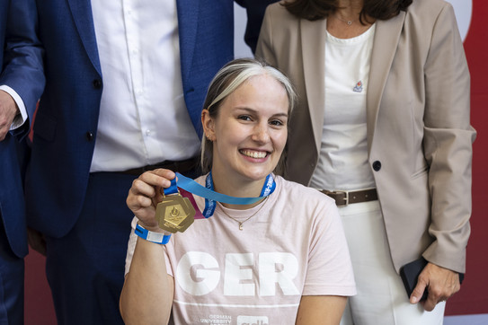 Foto: Eine Rollstuhlbasketballerin hält eine Goldmedaille hoch.