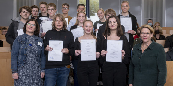 SchülerUni 2022 Gruppenfoto von Schüler*innen, die Urkunden in die Kamera halten.