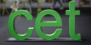 Logo cet Drei grüne Buchstaben c e t stehen in einem Raum