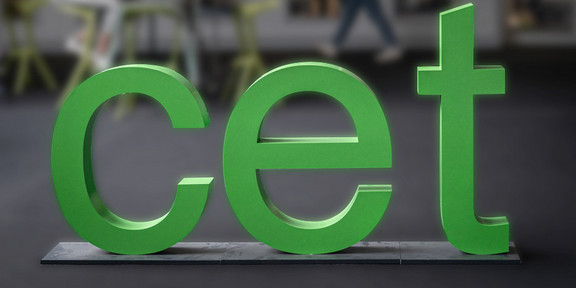 Drei grüne Buchstaben c e t stehen in einem Raum