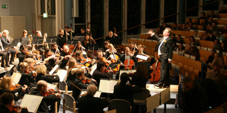 Ein Orchester spielt in einem verdunkelten Hörsaal
